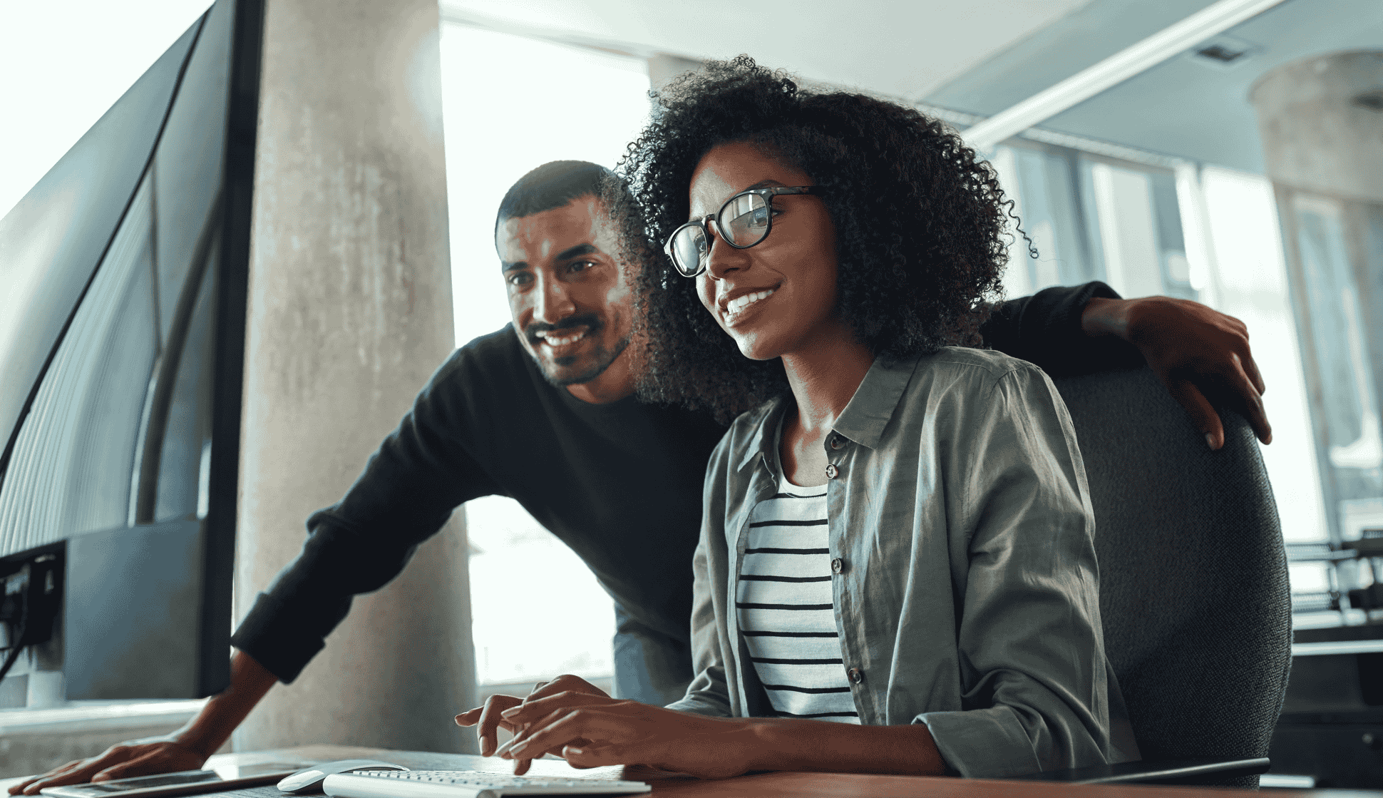 Smiling man and woman look review what's on a computer screen